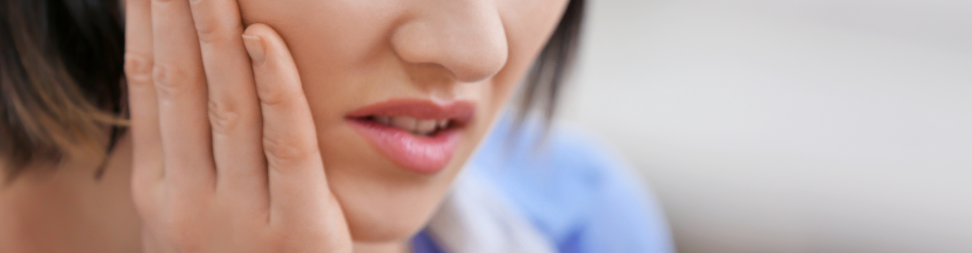 Woman holding her cheek in pain.